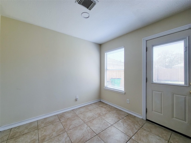 interior space with light tile patterned floors, visible vents, and baseboards