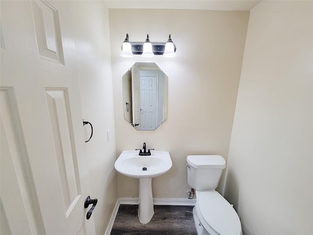 half bath with wood finished floors, toilet, and baseboards