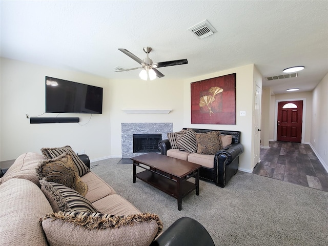 living area with a fireplace with flush hearth, visible vents, ceiling fan, and baseboards