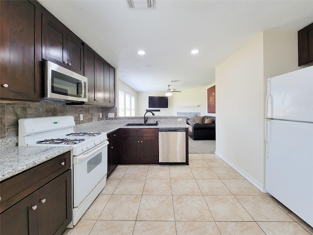 kitchen with light tile patterned flooring, a sink, open floor plan, dark brown cabinets, and appliances with stainless steel finishes