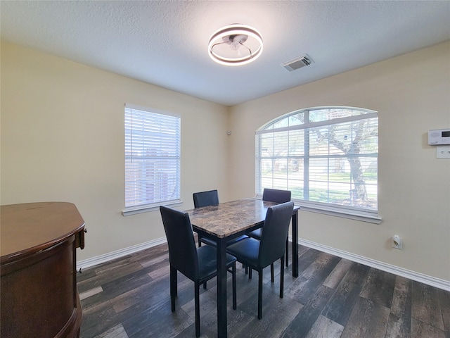 dining area featuring baseboards, a textured ceiling, visible vents, and dark wood-type flooring