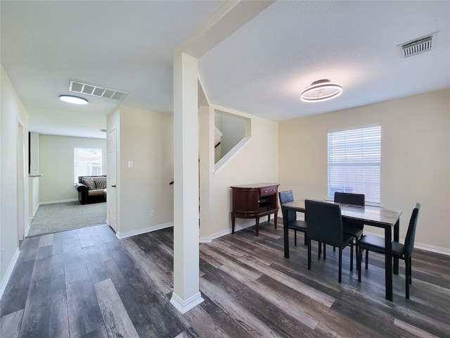 dining area with dark wood finished floors, visible vents, and baseboards