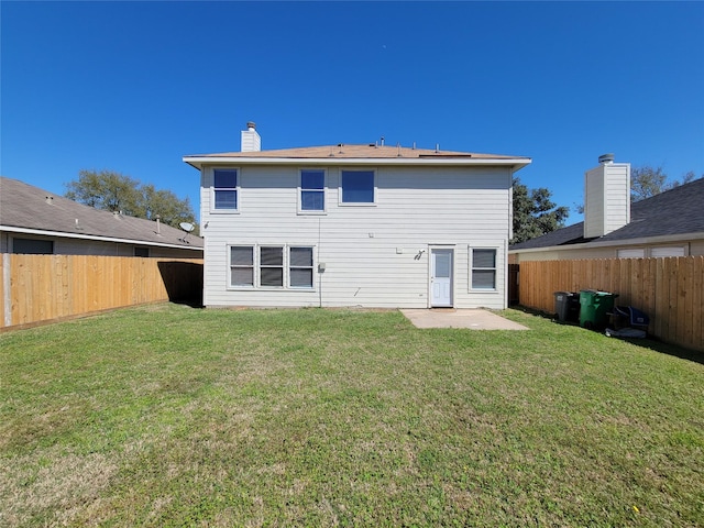 rear view of house featuring a fenced backyard, a lawn, and a chimney