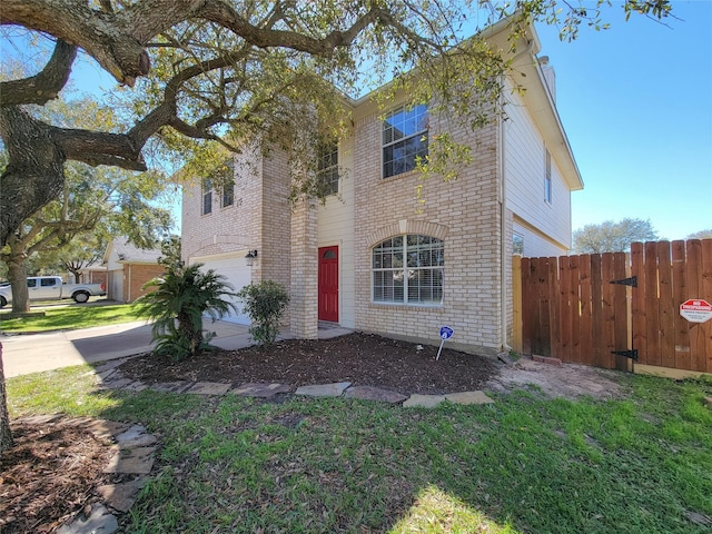 traditional-style home featuring brick siding, an attached garage, a front yard, fence, and driveway