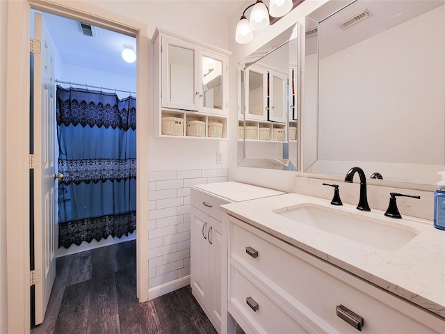 bathroom with tile walls, visible vents, vanity, and wood finished floors