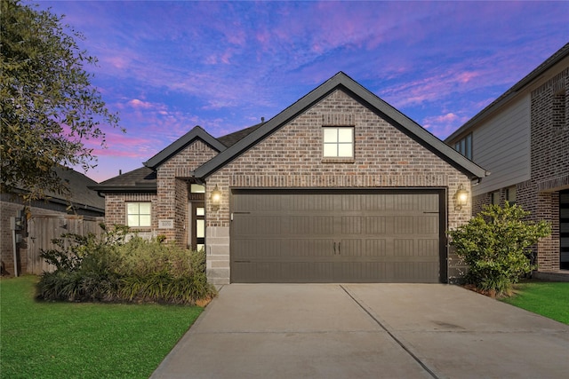 french country style house with brick siding, concrete driveway, a lawn, fence, and a garage