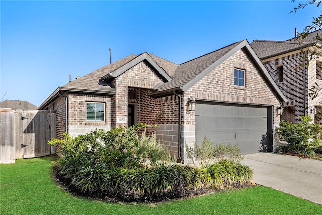 french country home with brick siding, a shingled roof, a garage, driveway, and a front lawn