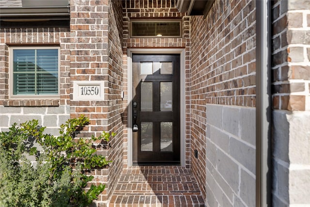 view of exterior entry featuring brick siding