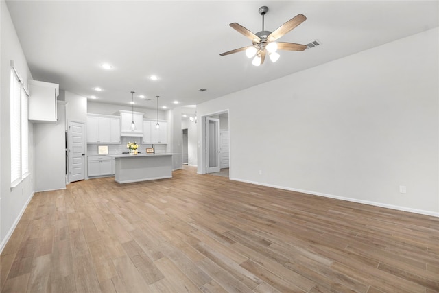 unfurnished living room featuring light wood-type flooring, visible vents, ceiling fan, and baseboards