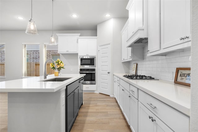 kitchen with light wood finished floors, stainless steel appliances, light countertops, white cabinetry, and a sink