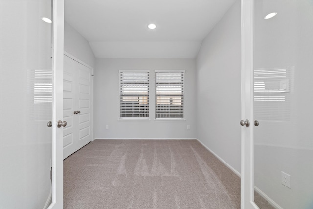 spare room featuring vaulted ceiling, carpet floors, recessed lighting, and baseboards