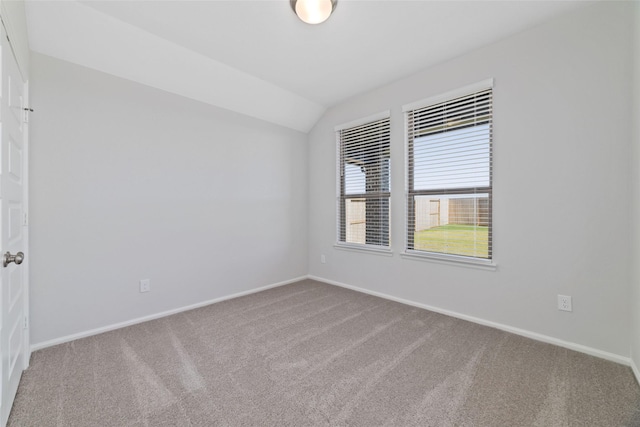 empty room featuring carpet, lofted ceiling, and baseboards