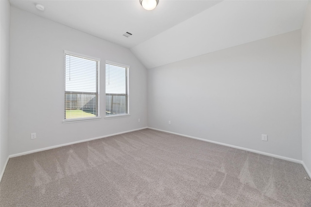 unfurnished room with vaulted ceiling, carpet floors, visible vents, and baseboards