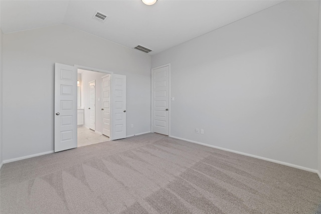 unfurnished bedroom with lofted ceiling, carpet flooring, visible vents, and baseboards