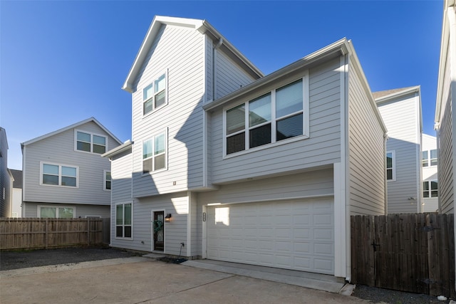 rear view of house featuring a garage, fence, and concrete driveway