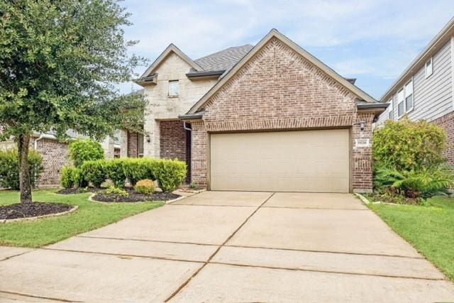 view of front facade featuring a front lawn, concrete driveway, brick siding, and an attached garage