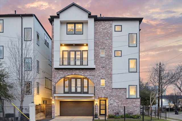 view of front facade featuring a fenced front yard, brick siding, a balcony, and stucco siding