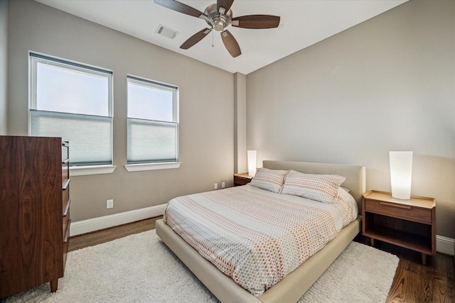 bedroom with ceiling fan, wood finished floors, visible vents, and baseboards