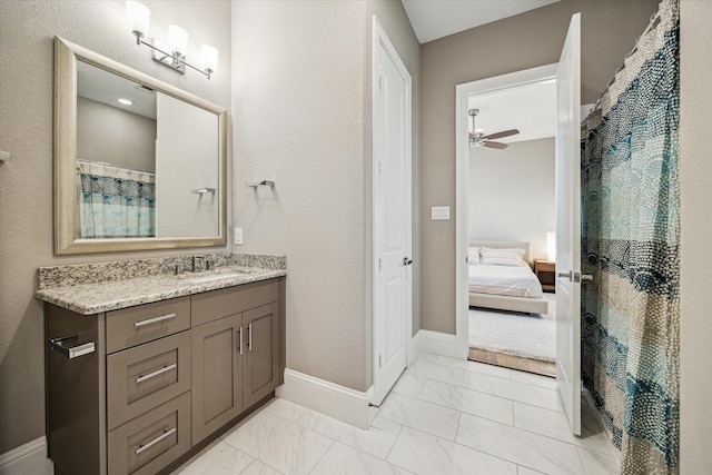 ensuite bathroom with a ceiling fan, marble finish floor, vanity, and baseboards