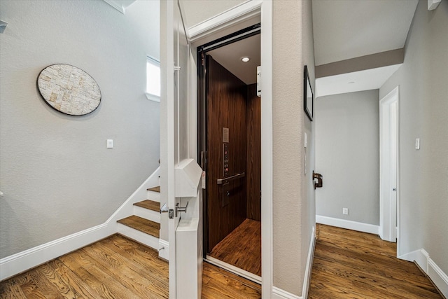 stairs featuring elevator, baseboards, and wood finished floors