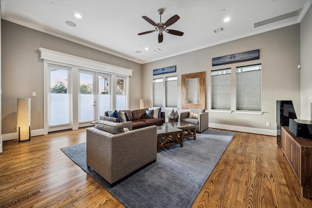 living area featuring baseboards, visible vents, crown molding, and wood finished floors