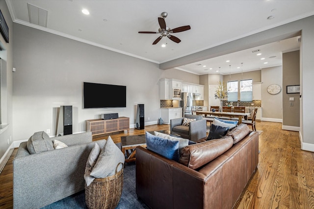 living area featuring recessed lighting, baseboards, crown molding, and light wood finished floors