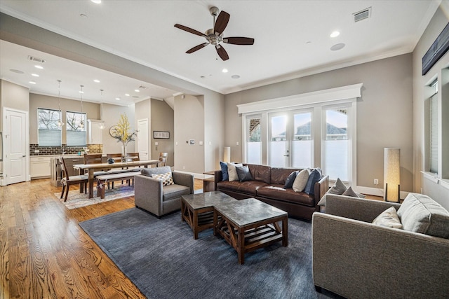 living room with crown molding, visible vents, plenty of natural light, and wood finished floors