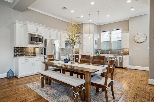 dining space with baseboards, light wood finished floors, and crown molding