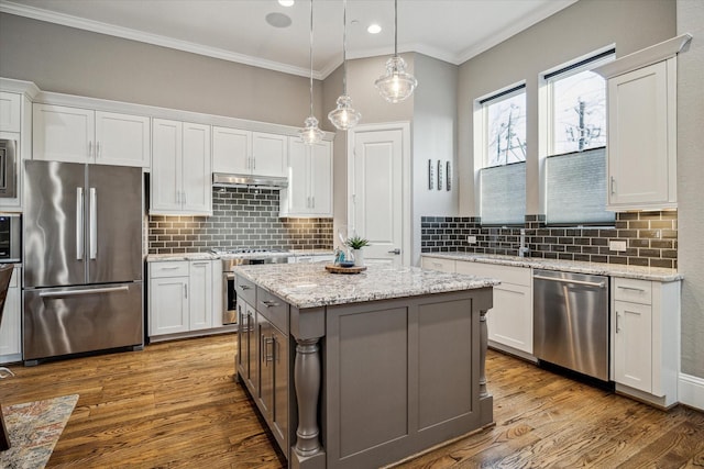 kitchen featuring under cabinet range hood, white cabinetry, appliances with stainless steel finishes, and wood finished floors