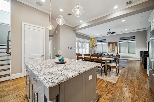 kitchen featuring ornamental molding, light wood-type flooring, visible vents, and a kitchen island