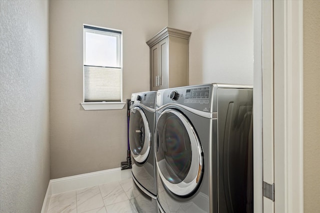 laundry area with washing machine and dryer, marble finish floor, cabinet space, and baseboards