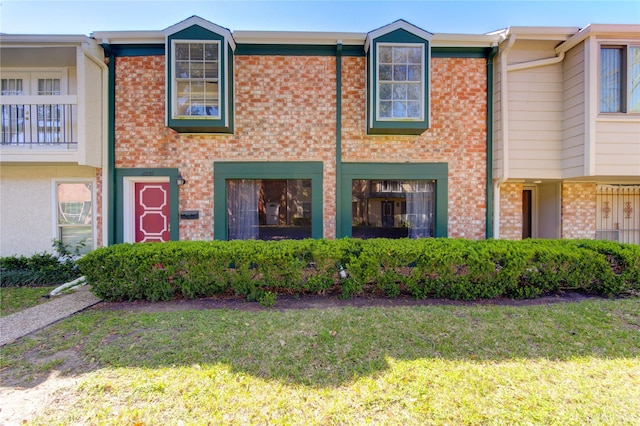 view of property with a front yard and brick siding