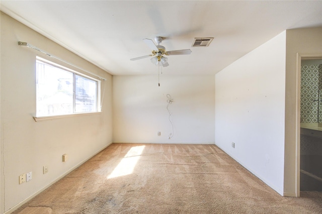 carpeted spare room with visible vents and a ceiling fan