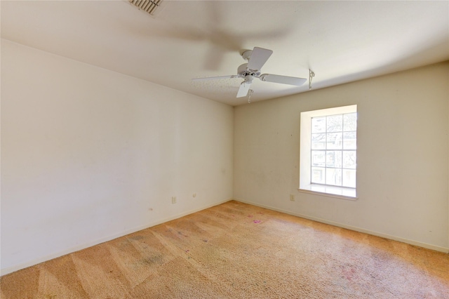 spare room with light carpet, baseboards, visible vents, and a ceiling fan