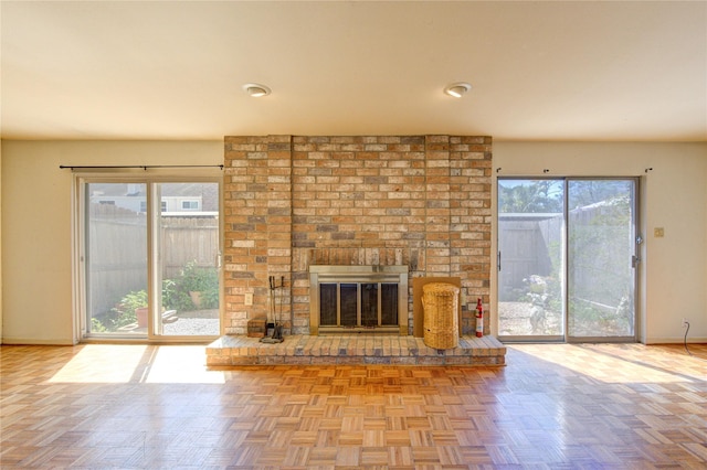 unfurnished living room featuring a brick fireplace and baseboards