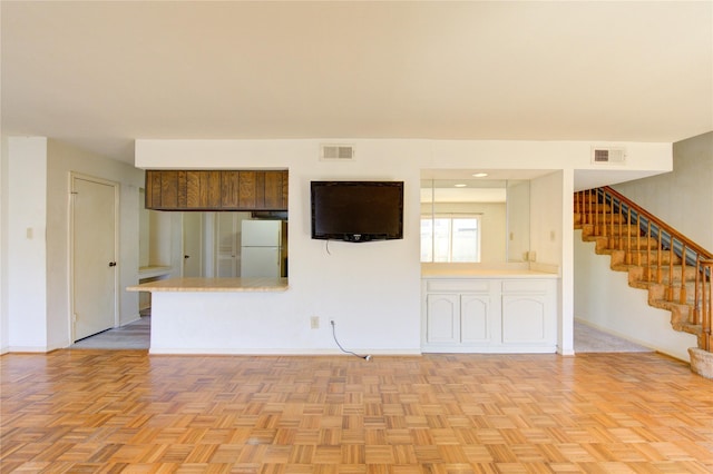 unfurnished living room featuring stairs, visible vents, and baseboards