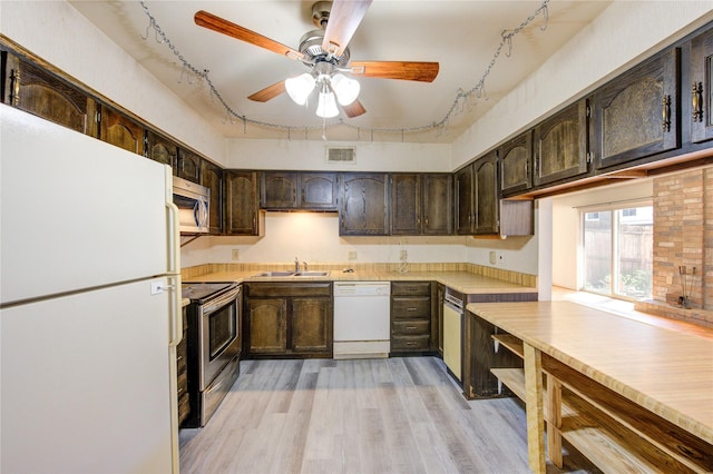 kitchen featuring dark brown cabinetry, visible vents, appliances with stainless steel finishes, light countertops, and a sink