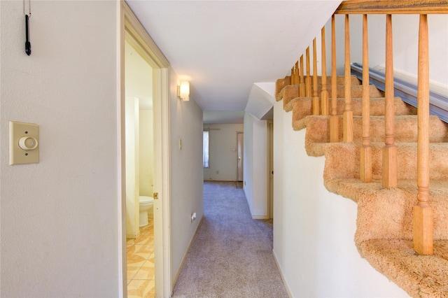 corridor with carpet floors, stairs, and baseboards