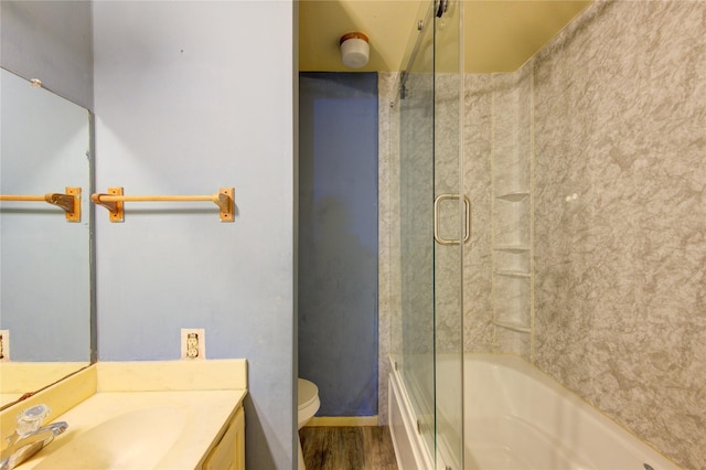 bathroom featuring toilet, bath / shower combo with glass door, wood finished floors, and vanity