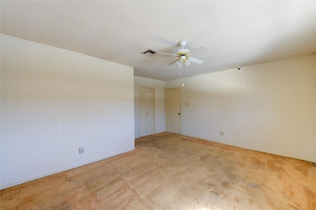 carpeted spare room with visible vents and a ceiling fan