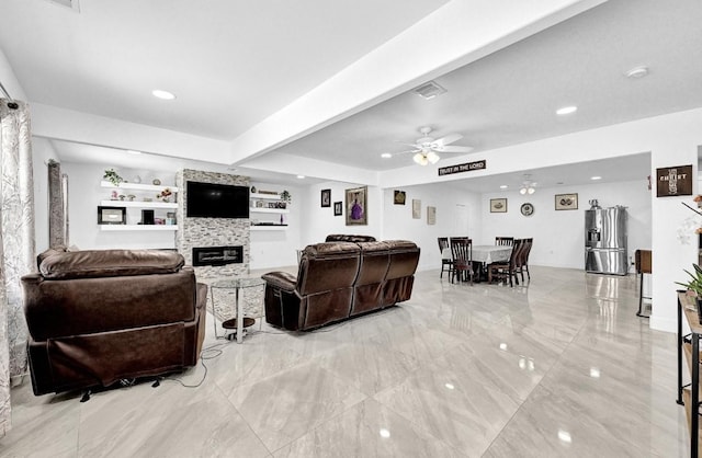 living room featuring a large fireplace, marble finish floor, visible vents, and a ceiling fan