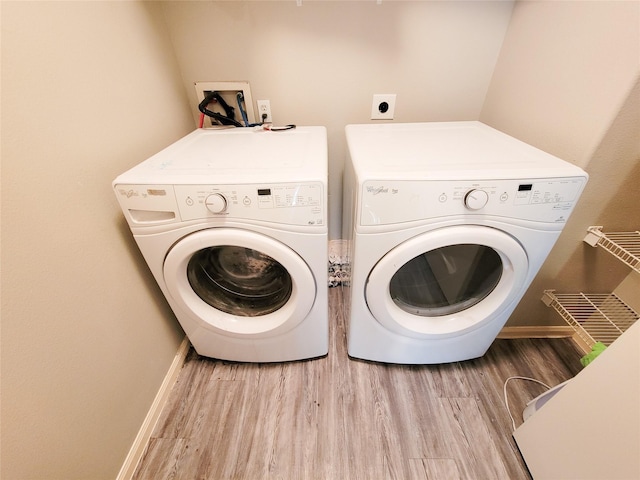 clothes washing area featuring baseboards, washer and clothes dryer, and wood finished floors