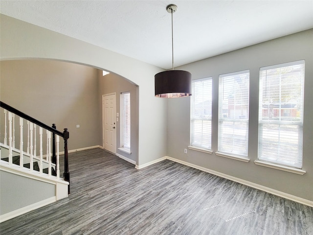 foyer with baseboards, stairs, arched walkways, and wood finished floors