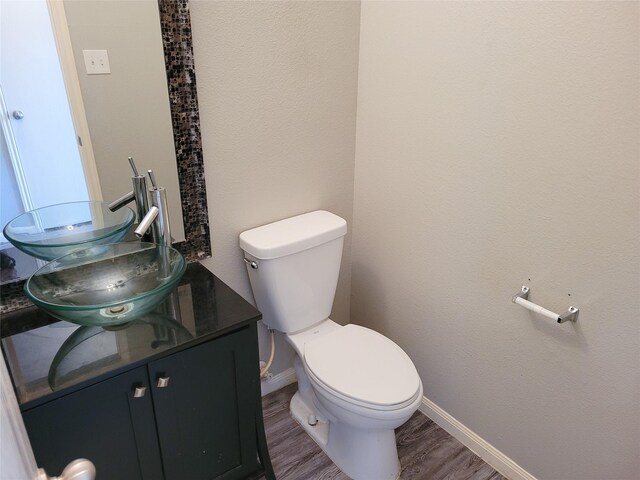 bathroom featuring toilet, baseboards, wood finished floors, and vanity