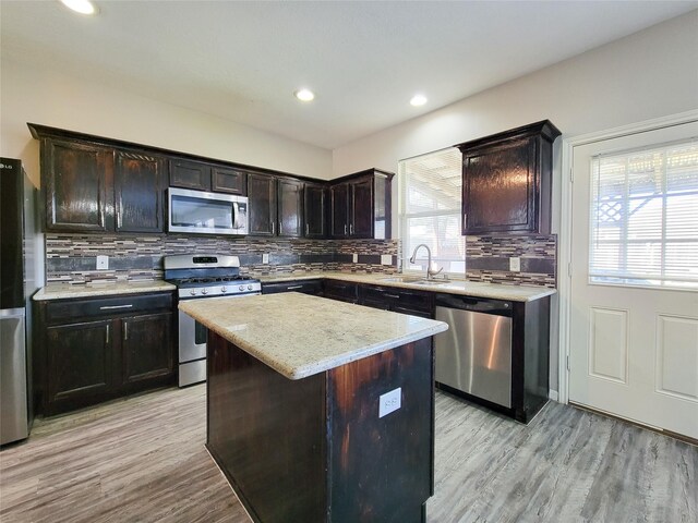 kitchen with stainless steel appliances, light wood-type flooring, a center island, and a sink