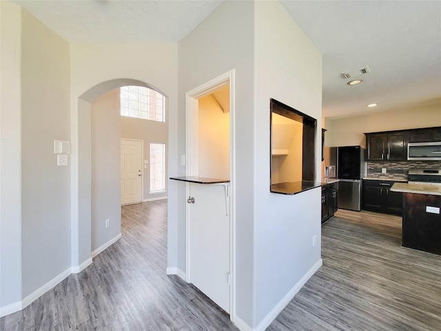 kitchen featuring arched walkways, appliances with stainless steel finishes, wood finished floors, and visible vents