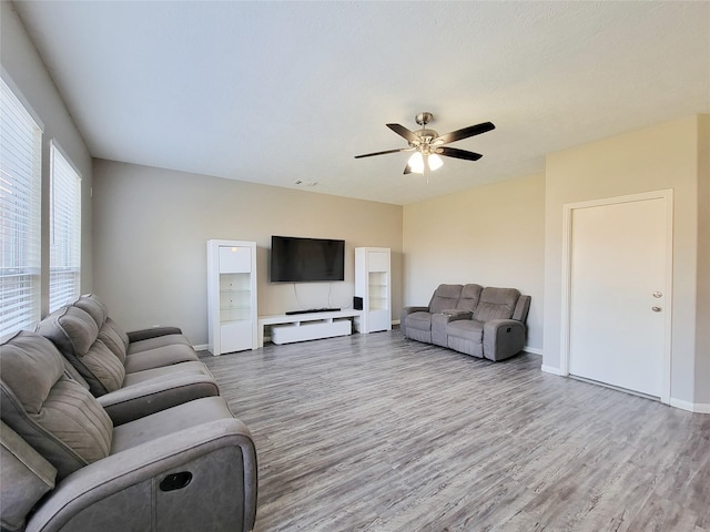 living area with wood finished floors, a ceiling fan, and baseboards