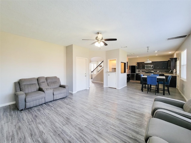 living room featuring light wood finished floors, baseboards, and arched walkways