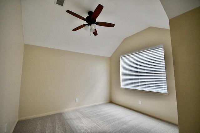 spare room with carpet floors, visible vents, baseboards, vaulted ceiling, and a ceiling fan