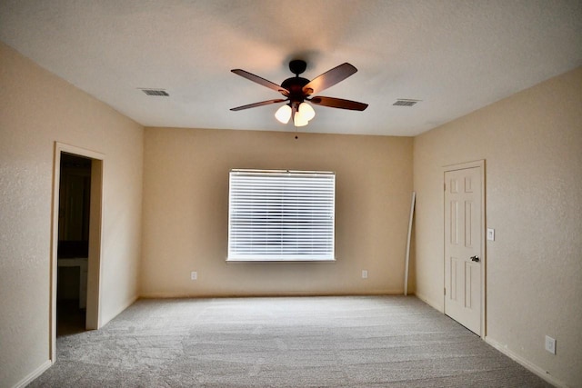 empty room featuring carpet, visible vents, and a ceiling fan